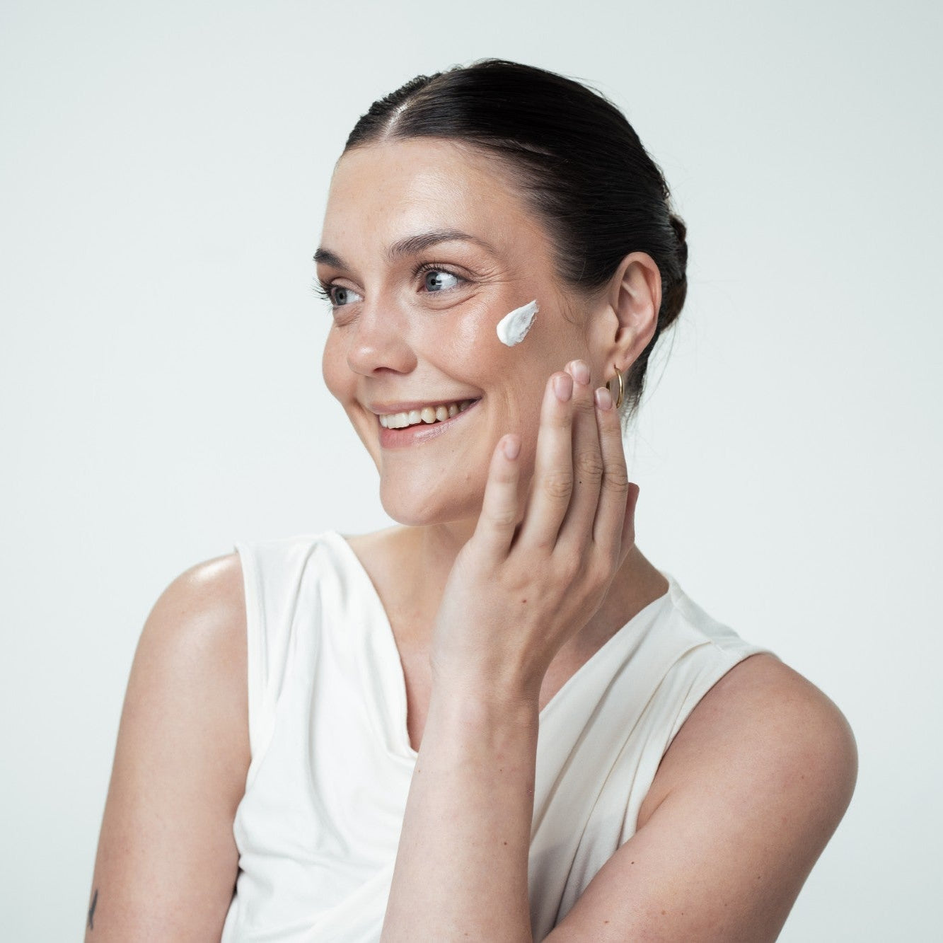 Woman applying cream to her face with a white background